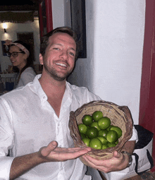 a man holds a basket of limes in his hands