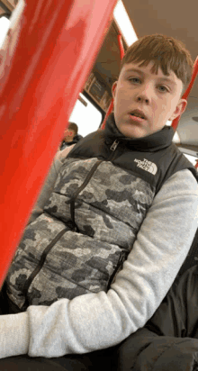 a young boy wearing a vest that says the north face