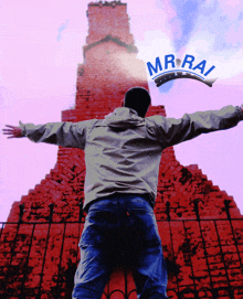 a man with his arms outstretched is standing in front of a brick building with the word mr.rai on the top