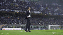 a man in a suit stands on a soccer field with a banner that says trusted by inter on it