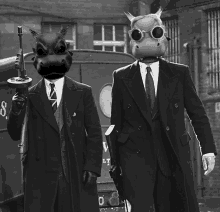 two men in suits and gas masks are standing next to each other in front of a van that has the letter v on it