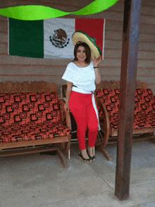 a woman stands in front of a mexican flag holding a sombrero