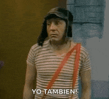 a man wearing a hat and a striped shirt is standing in front of a wall and says yo tambien .