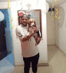 a man is holding a dog in a hallway with balloons and confetti