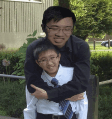 a man wearing glasses is hugging a boy wearing a blue tie