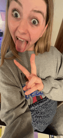 a woman wearing a dodgers sweatshirt sticks her tongue out