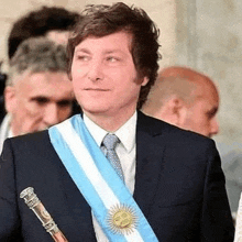 a man in a suit and tie is wearing a sash with the flag of argentina .