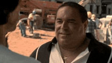 a man wearing a cross necklace is talking to another man at a construction site .