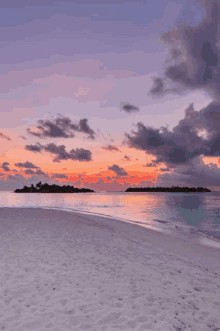 a beach with a sunset in the background and a small island in the distance