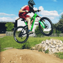 a young boy wearing a helmet is riding a green bicycle