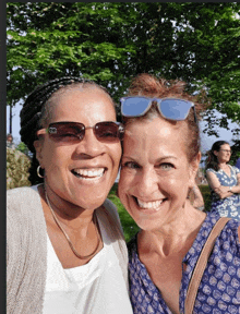 two women posing for a picture with one wearing sunglasses and the other wearing a white shirt