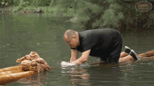 a man in a black shirt is kneeling in a body of water with a watermark that says ' expedition warrior '