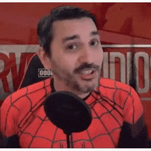 a man wearing a spiderman costume is talking into a microphone .