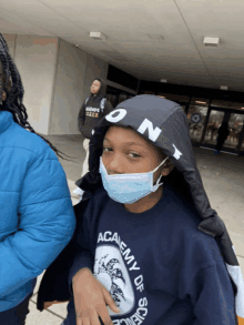 a boy wearing a mask and academy of science sweatshirt