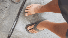 a person wearing flip flops stands on a concrete surface