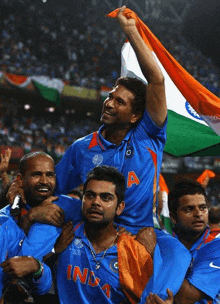 a man wearing a blue india jersey is being carried by other men