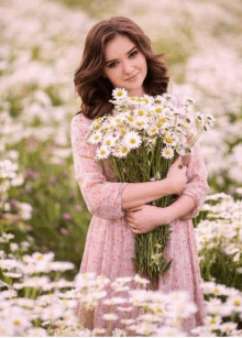 a woman in a pink dress holding a bouquet of daisies