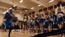 cheerleaders and a basketball player in a gym with a banner on the wall that says ' kings ' on it