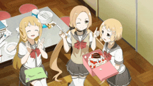 three anime girls are standing around a table holding a cake and a box that says happy birthday