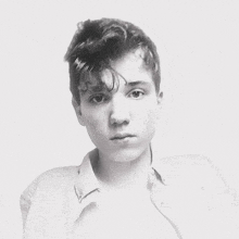 a black and white photo of a young man with a button up shirt on