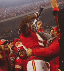 a man in a red shirt is being lifted in the air by his teammates