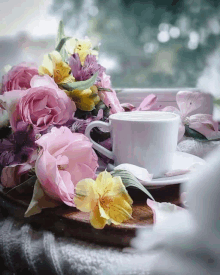 a cup of coffee sits on a saucer next to flowers