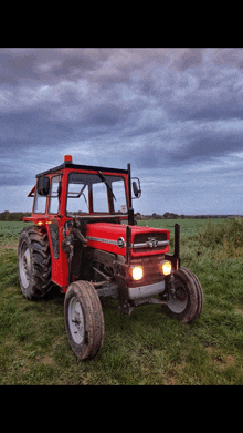 a red massey ferguson tractor is parked on a grassy field