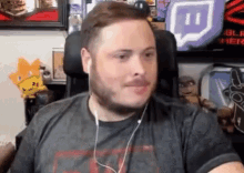 a man wearing headphones is sitting in a chair in front of a twitch logo .