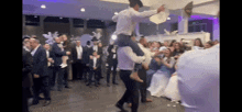 a man in a cowboy hat is carrying another man on his shoulders at a wedding reception