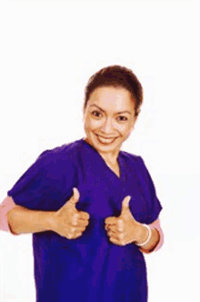 a woman in a blue scrub is giving a thumbs up sign