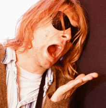 a man with red hair wearing sunglasses and a striped shirt yawning