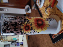 a tumbler with a sunflower design on it sits on a table