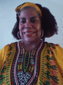 a woman wearing a yellow shirt and a headband smiles at the camera