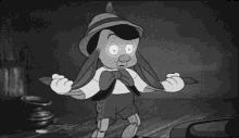 a black and white photo of a cartoon character , pinocchio , standing on a wooden floor .