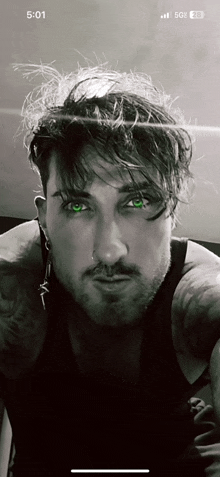 a black and white photo of a man 's face with green eyes