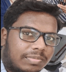 a man with a beard and glasses is smiling for the camera .