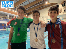 three young men are posing for a picture with medals around their necks in front of a pool with tuffi blog in the background