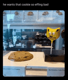 a chocolate chip cookie and a bumblebee cake pop are on display in a bakery