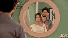 a man and woman are looking at themselves in a mirror with kk written on the bottom right