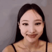 a close up of a woman making a funny face while wearing a black tank top .