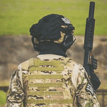 a man in a military uniform is holding a gun and wearing a helmet