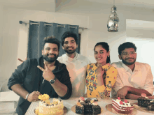 a group of people are posing for a picture with cakes on the table