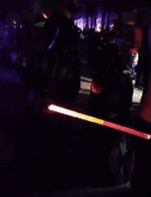 a person holding a red and yellow light stick in the dark