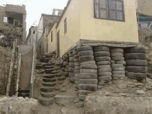 a house is sitting on top of a pile of tires with stairs leading up to it .