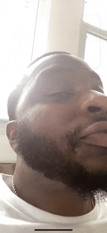 a close up of a man 's face with a beard and a white shirt .