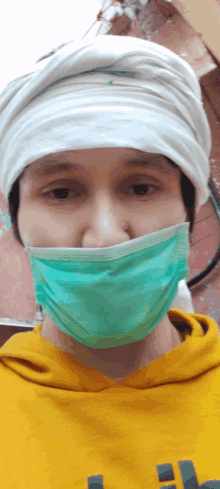 a person wearing a yellow hoodie and a green mask on their face