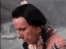 a man in a native american costume is holding his shoulder and looking down .