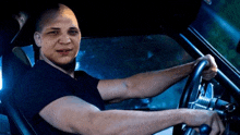 a bald man in a black shirt is holding a steering wheel