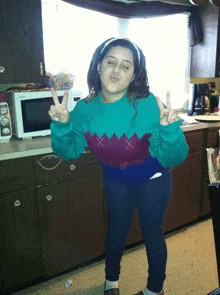 a girl in a green sweater giving a peace sign