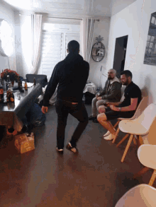 a group of people are gathered in a living room with a box on the floor that says ' ice ' on it